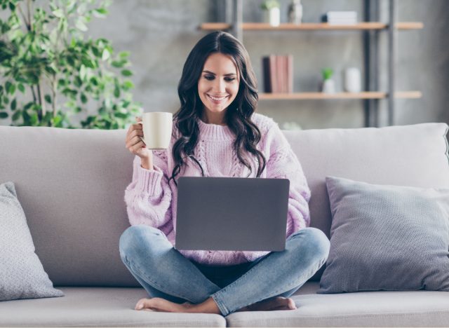 The #1 Virtual Wellness Retreat You Won't Want To Miss — Eat This Not That - Eat This, Not That 5 woman in purple sweater sits on couch while watching virtual event on laptop