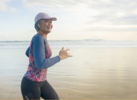 happy woman over 40 runs on a beach