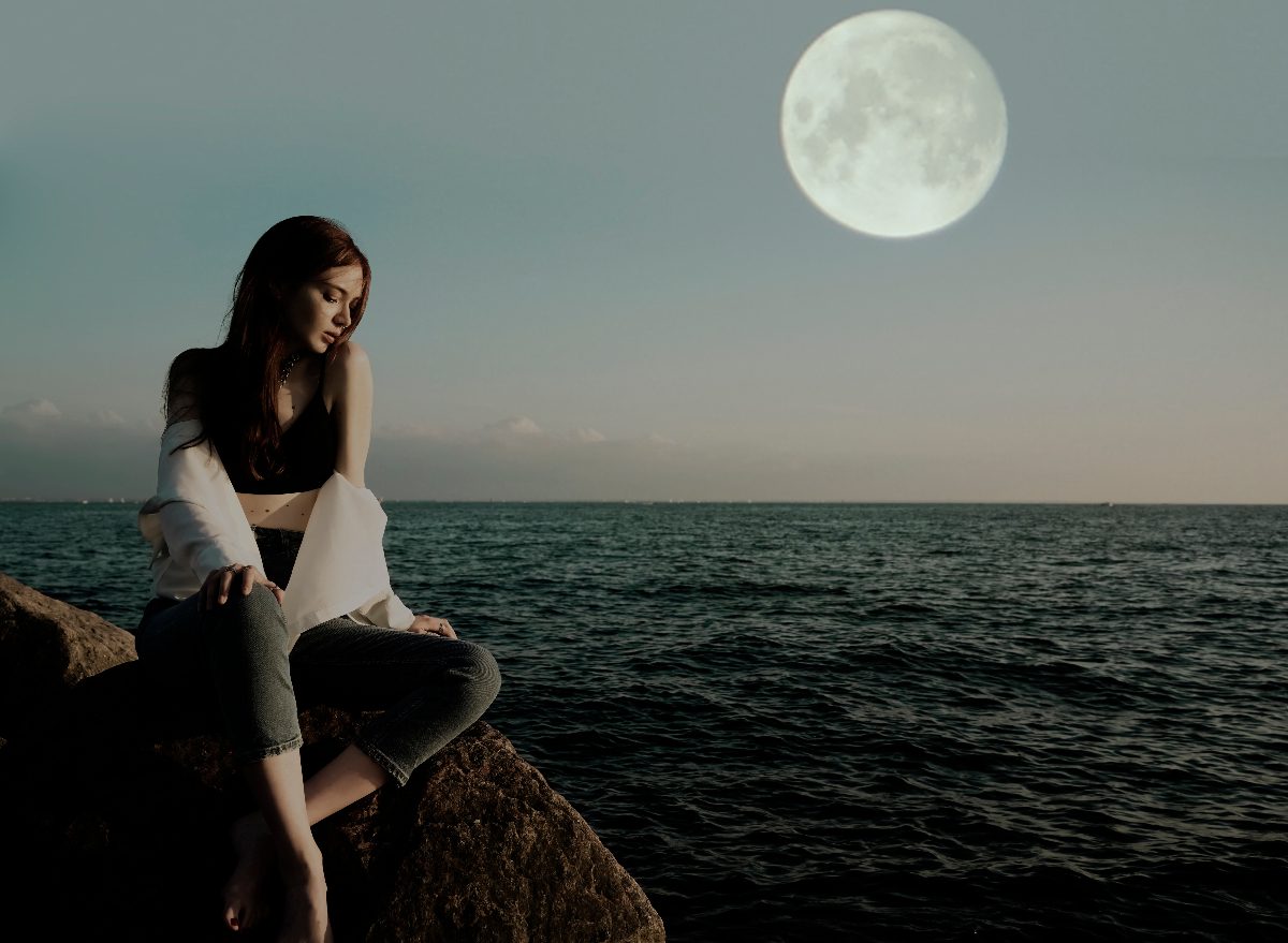 woman on rocky beach under moon