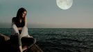 woman on rocky beach under moon