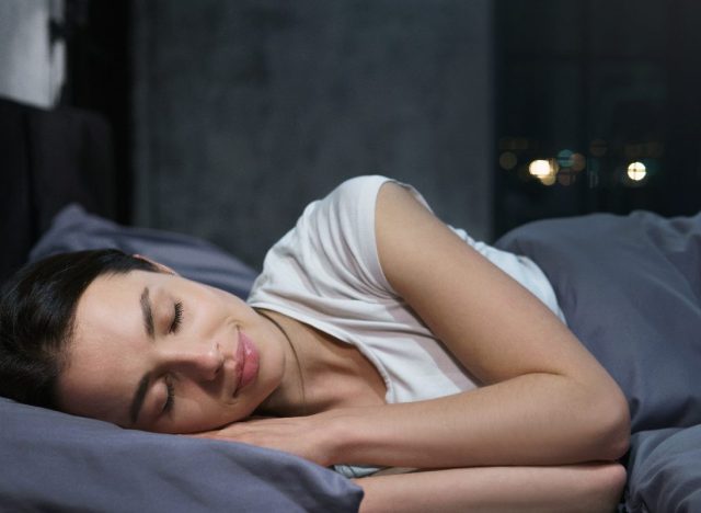 woman sleeps peacefully in plush gray bedding