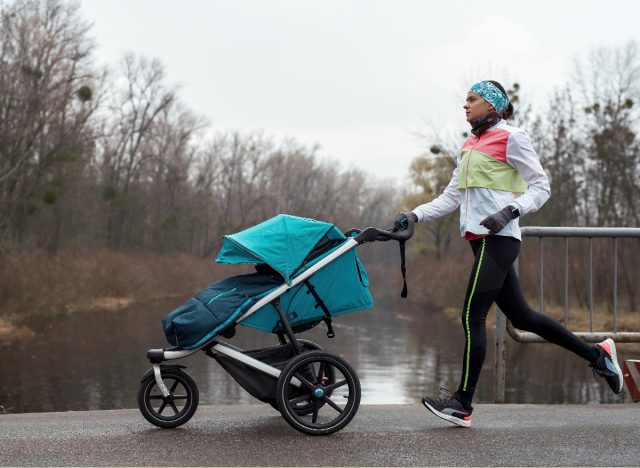 woman in workout attire jogs with baby stroller in the winter