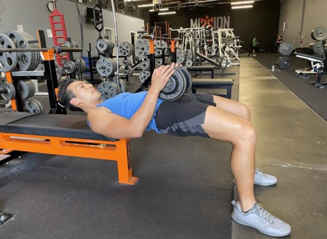 trainer doing dumbbell hip thrust