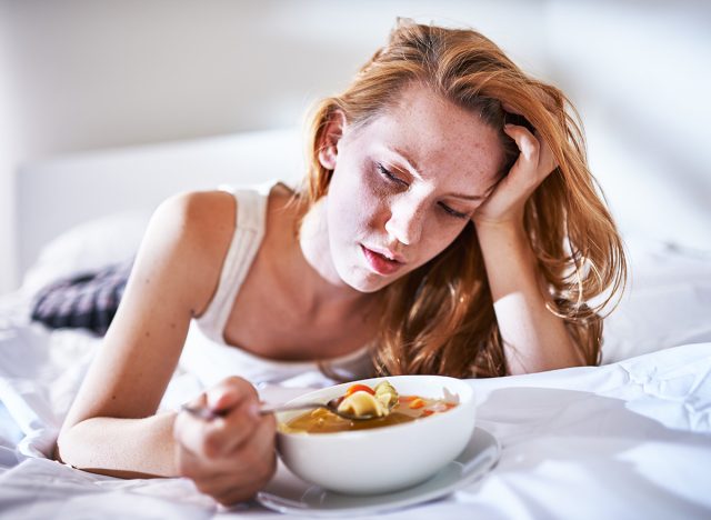 woman eating on the bed while feeling sick