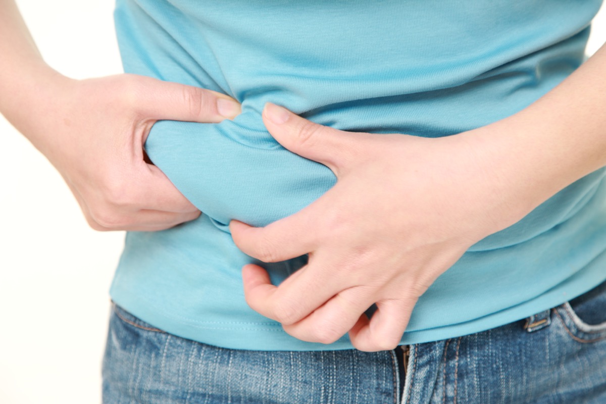 Closeup of woman pinching belly fat.