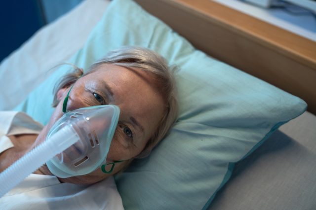 Close-up of covid-19 infected patient in bed in hospital, coronavirus and ventilation.