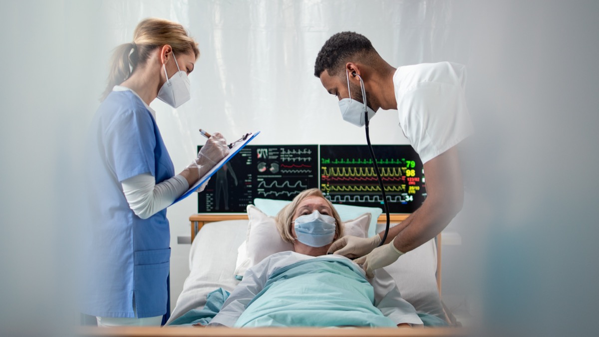Doctors and senior covid-19 infected patient in bed in hospital