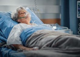 Elderly woman wearing oxygen mask sleeping in hospital bed