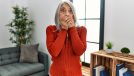 Middle age grey-haired woman wearing casual clothes standing at home shocked covering mouth with hands.