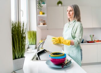 Grey-haired woman doing dishes dishwash.