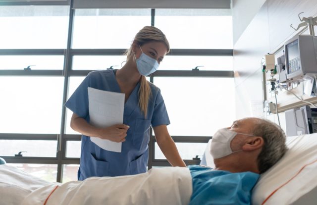 Infirmière portant un masque facial lors de la vérification d'un patient à l'hôpital pendant la pandémie de COVID-19.