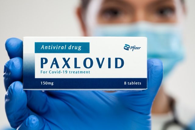dical worker holding medicine package box, Pfizer PAXLOVID antiviral drug, cure for Coronavirus infection, COVID-19 virus disease prevention