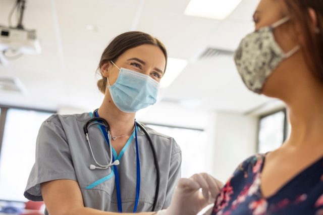 Friendly nurse preps patient prior to COVID-19 vaccine shot.