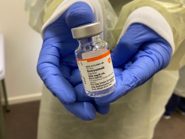 A person wearing full PPE holds a vial of sotrovimab medicine covid-19 virus treatment
