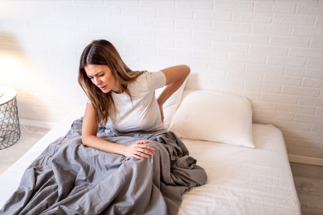 Woman in bed having backache.