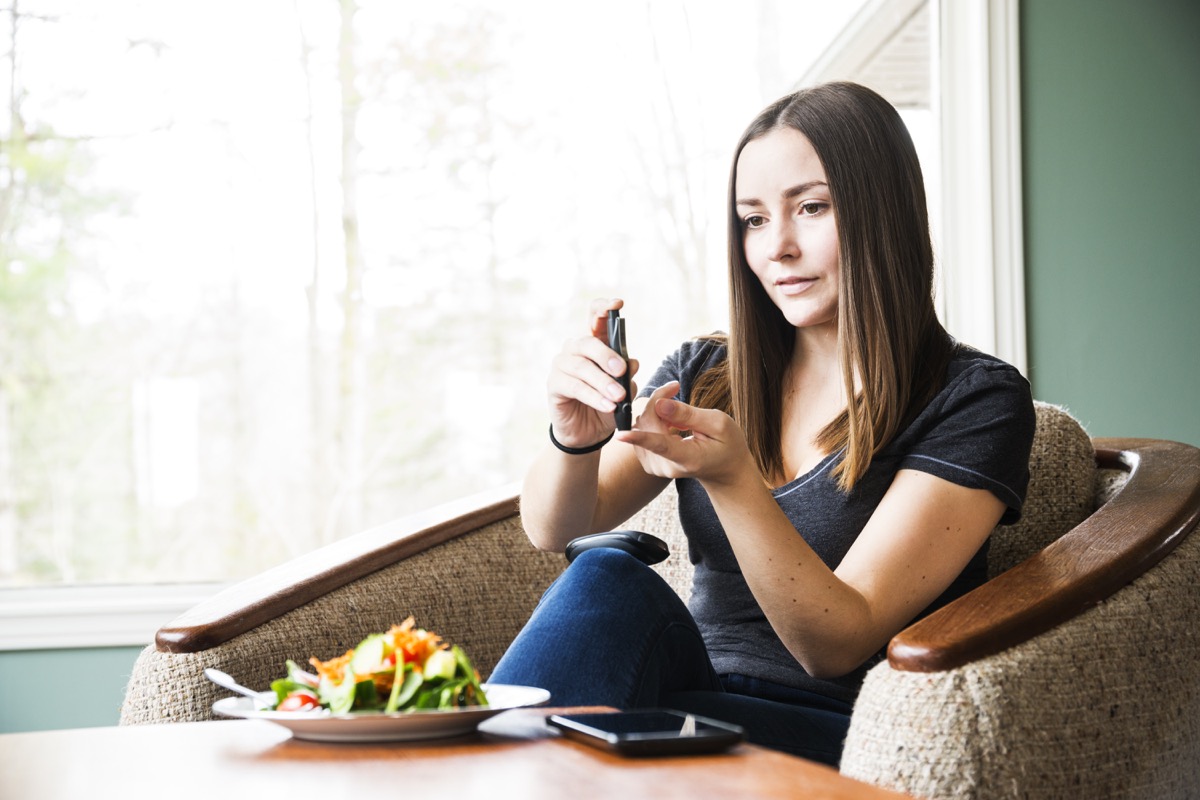 A young diabetic woman checking her blood sugar levels at home