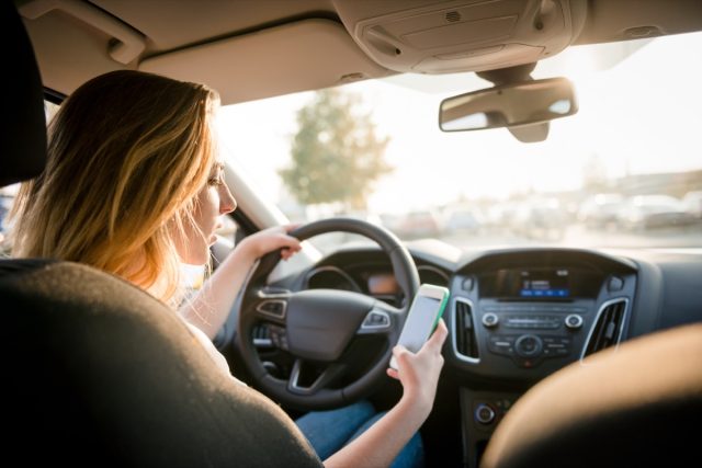 I'm a Doctor and Warn You Never Press This Button on Your Phone — Eat This Not That 31 Young woman looking to her smartphone while driving car