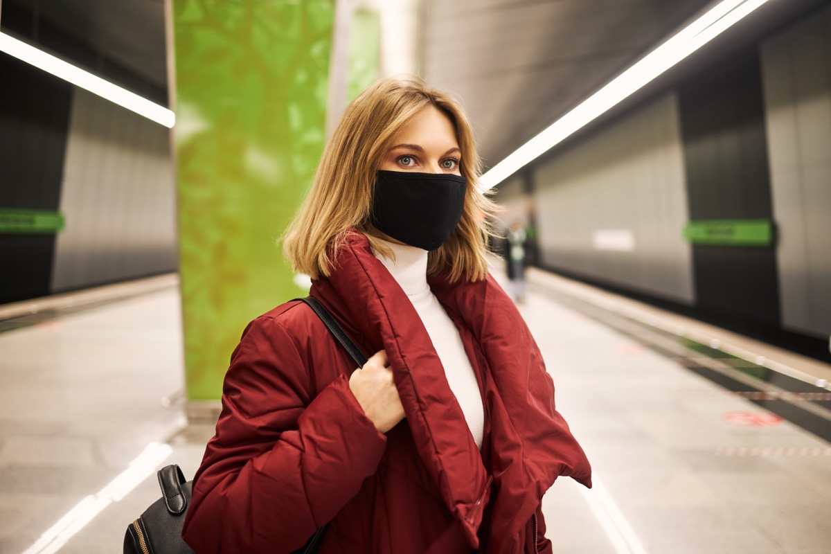 Woman in mask and red coat in the subway.