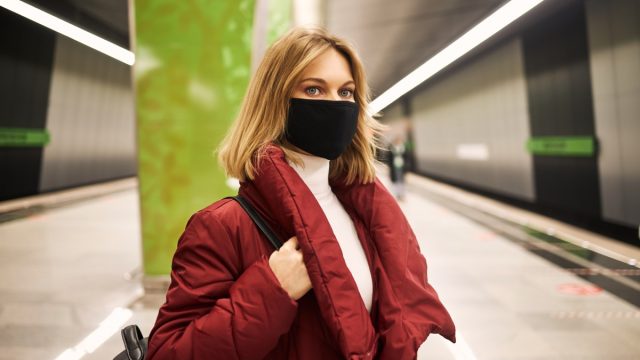 Woman in mask and red coat in the subway.