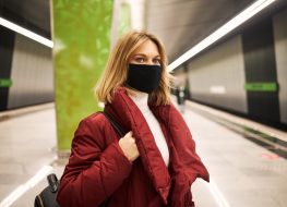 Woman in mask and red coat in the subway.