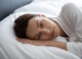 Woman awakened lying in bed with her eyes open.