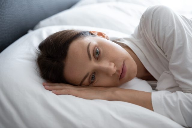 Woman awakened lying in bed with her eyes open.