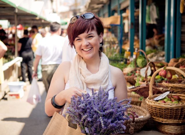 woman smiling at farmers market holding flowers