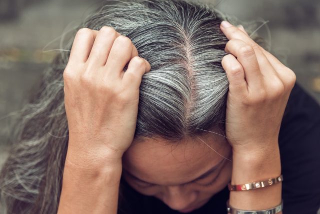 Closeup sad asian woman showing her gray hair.