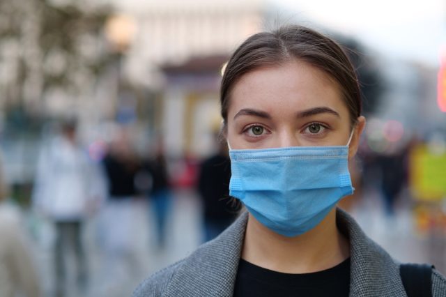 Young woman wearing protective mask on a crowded street