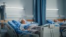 Elderly woman wearing oxygen mask sleeping in hospital bed.