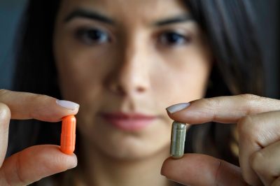 Young Hispanic woman choosing between antibiotics or alternative medicine.