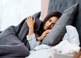 Woman recovering from an illness in bed at home.