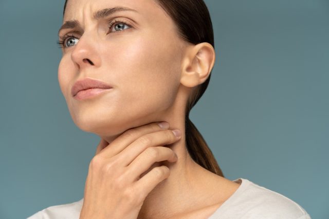 Closeup of sick woman having sore throat.