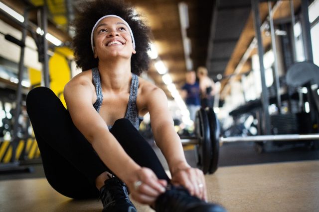 woman tying sneakers at gym
