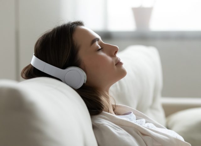 woman peacefully listening to music on headphones on couch