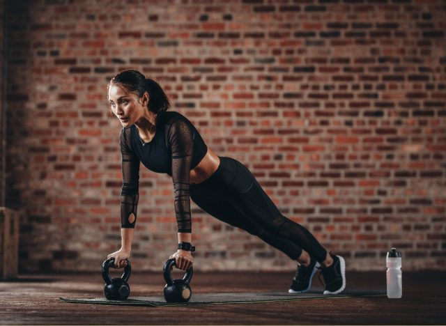 woman doing intense kettlebell workout in front of exposed brick