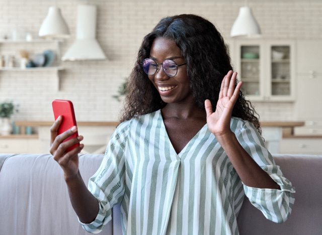 happy woman waves while on a virtual call