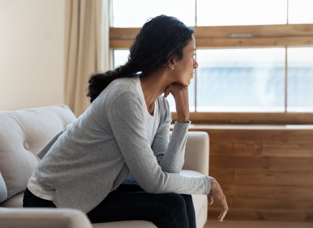 woman looking out the window experiencing cabin fever, mental health