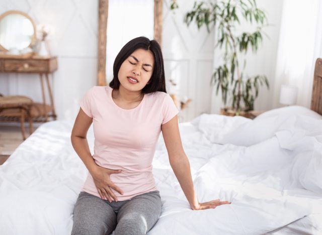 The woman is sitting in bed struggling with hip pain