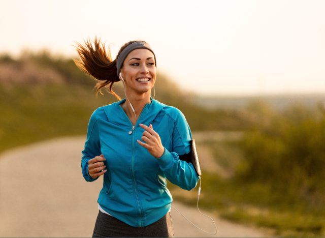 happy woman jogs along trail