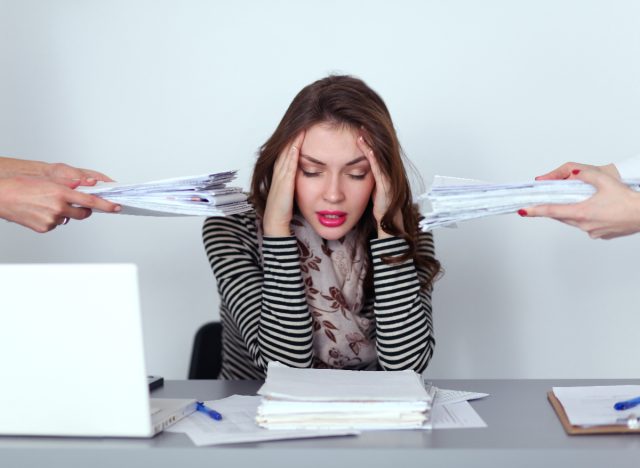 woman puts hands on head, stressed, busy at work