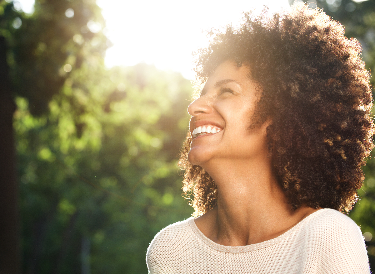 happy woman looks up at sky outdoors