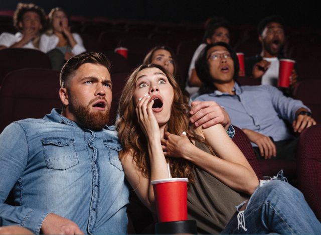 couple watches scary movie in theatre