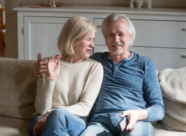 senior couple watches scary movie on couch