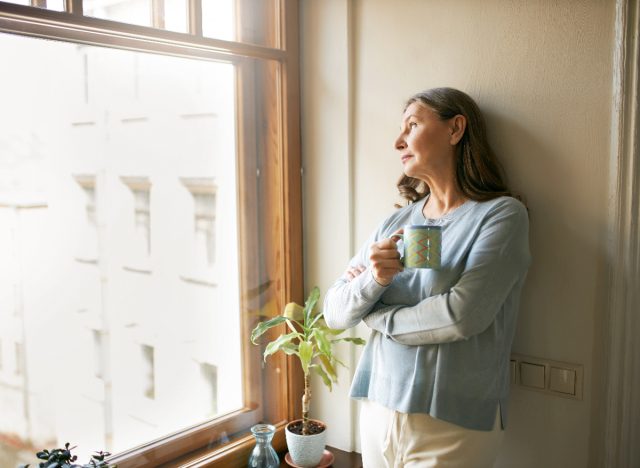 woman gazing outside holding coffee mug