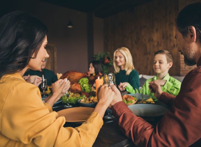 family holds hands while praying before dinner