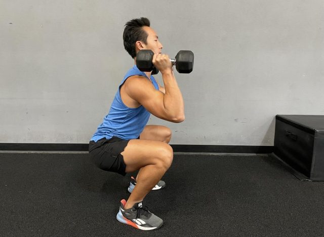 trainer doing dumbbell front squat to shrink belly fat faster