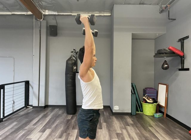 demonstrating dumbbell push press to get rid of a flabby stomach