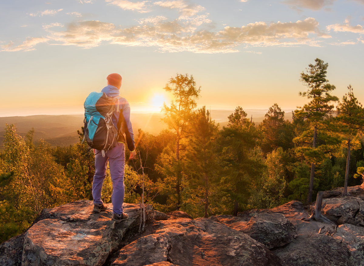 man looks out at horizon on sunset hike