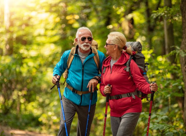 senior couple spring hiking with walking poles